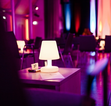 Der Raiffeisen Saal mit Beistelltischen und lila Beleuchtung bei dem Auftritt von Andreas Hofmeier im Forum Altötting.