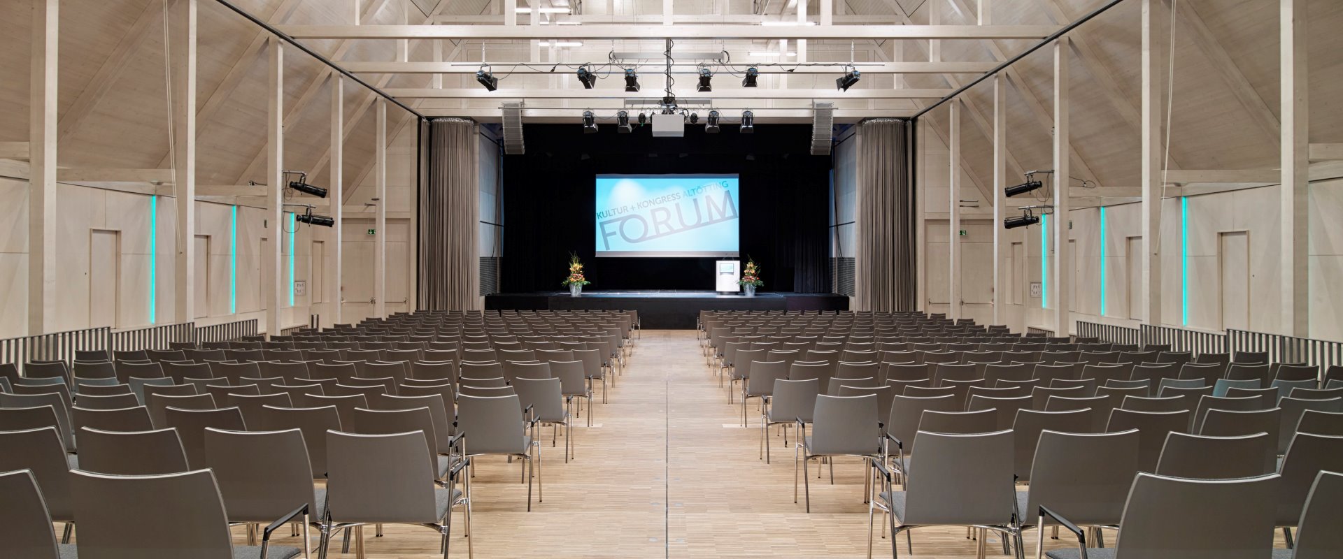 Der Raiffeisen-Saal mit Reihenbestuhlung, Leinwand und Rednerpult auf der Bühne im Forum Altötting.