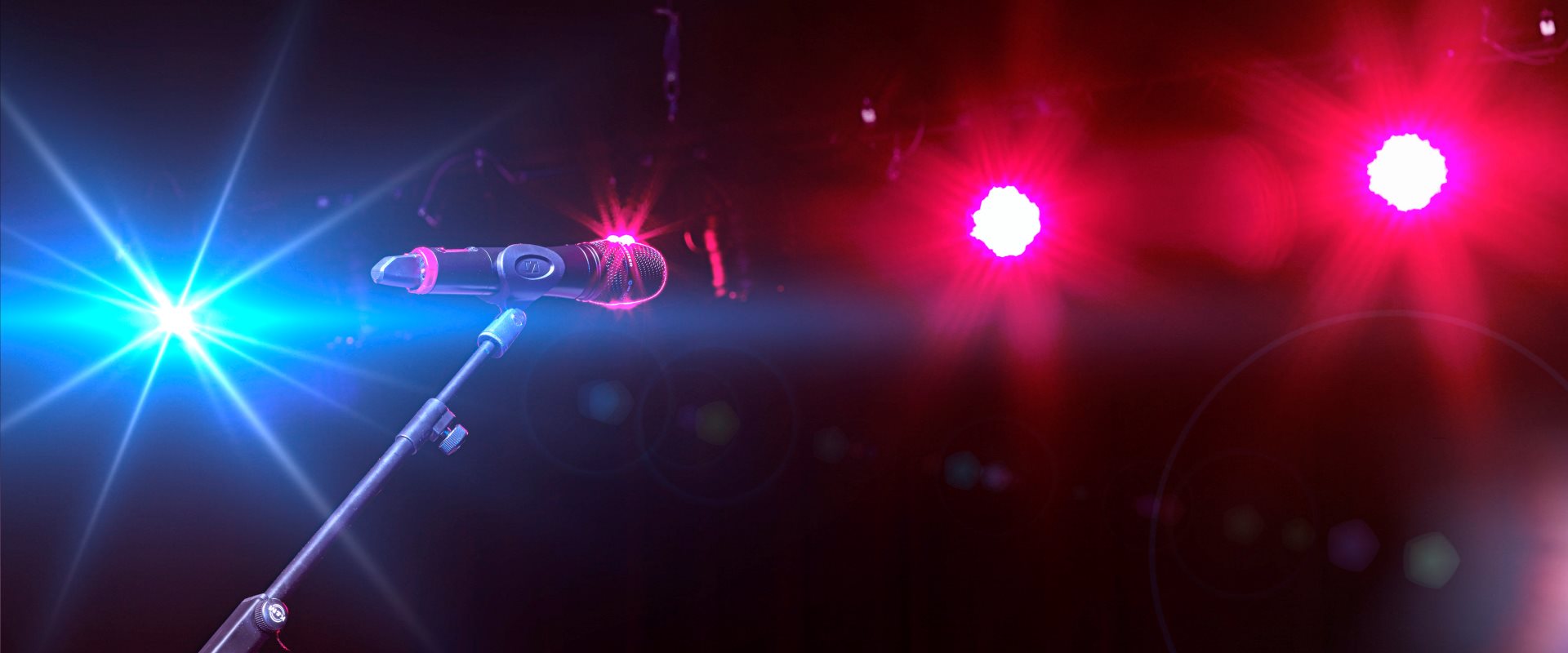 Die Lichteffekte in blau/pink mit einem Mikrofon und dem Ständer auf der Bühne im Raiffeisen Saal im Forum Altötting.